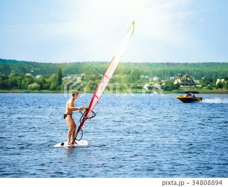 Windsurfer on the board with a white sail floating Windsurfer on the board with a white sail floating 34808894