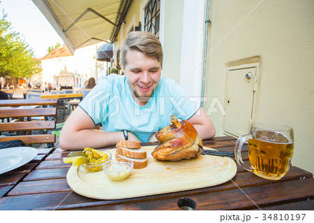 Young man eating smoked pork leg meat and drinking Young man eating smoked pork leg meat and drinking 34810197