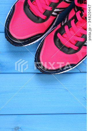 Pair of pink sport shoes on blue boards Pair of pink sport shoes on blue boards 34820447