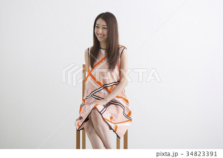 椅子に座るワンピースの女性の写真素材