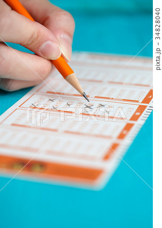 Picture of man's hand marking in lottery ticket 34828040
