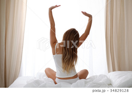 Woman stretching in bed after wake up, back view 34829128