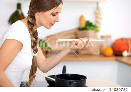 Young woman is cooking in a kitchen. Housewife is 34829786