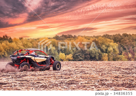 Racing quad bike in field under dramatic sunset Racing quad bike in field under dramatic sunset 34836355