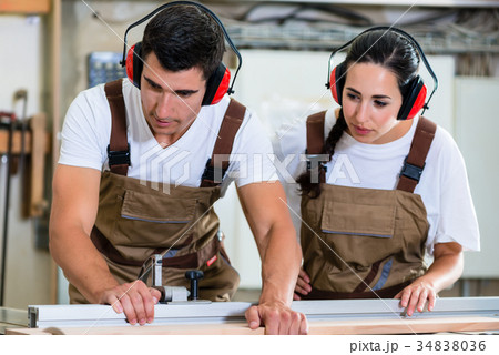 Carpenter and apprentice working together in 34838036