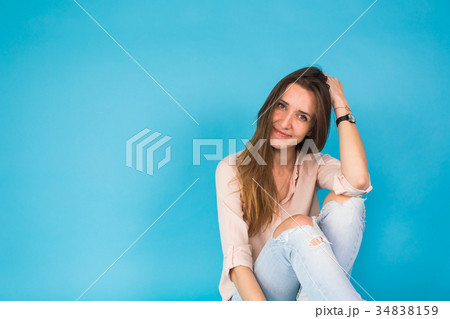 Hipster girl sitting on floor against blue Hipster girl sitting on floor against blue 34838159