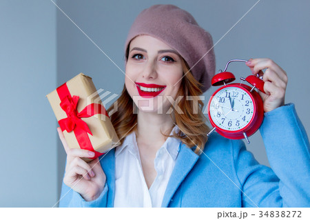 woman in beret with Christmas gift and alarm clock 34838272
