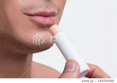 Cute nude guy is using cosmetic balm 34839088