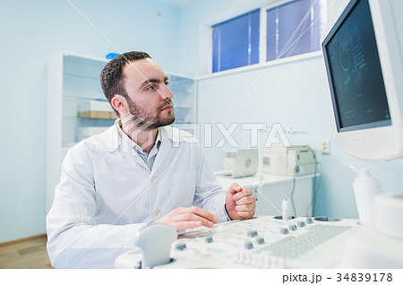 handsome doctor using an ultrasound machine 34839178