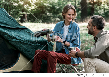 Joyful lovers drinking hot beverage in forest Joyful lovers drinking hot beverage in forest 34839949