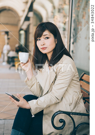ベンチでコーヒーを飲みながらスマホを見る女性 ベンチでコーヒーを飲みながらスマホを見る女性 34843022