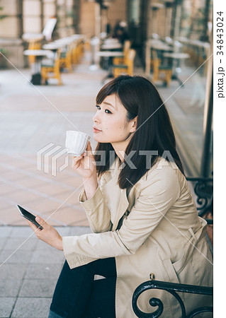 ベンチでコーヒーを飲みながらスマホを見る女性 ベンチでコーヒーを飲みながらスマホを見る女性 34843024