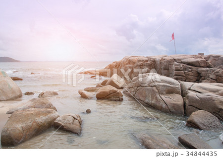Flag is fluttering on the wind in stones near sea Flag is fluttering on the wind in stones near sea 34844435