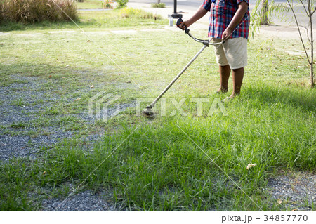 Senior worker mow grass with electric hand trimmer Senior worker mow grass with electric hand trimmer 34857770