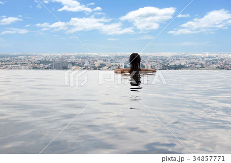 Young woman in swimming pool with city view 34857771