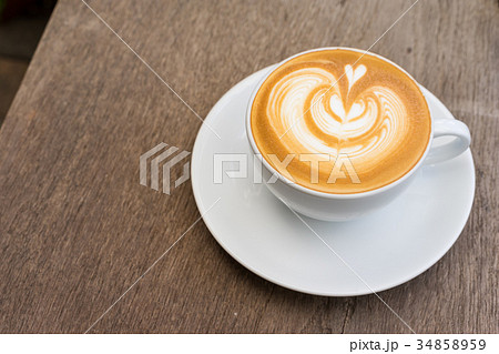 A white cup of coffee latte art on wood table 34858959
