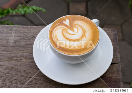 A white cup of coffee latte art on wood table 34858962