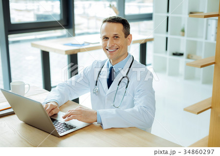 Handsome smart doctor using a laptop 34860297