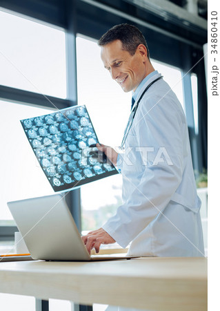 Cheerful handsome radiologist using a laptop 34860410
