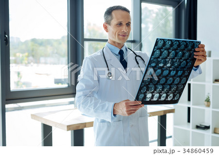 Delighted smart neurologist holding an X ray scan 34860459