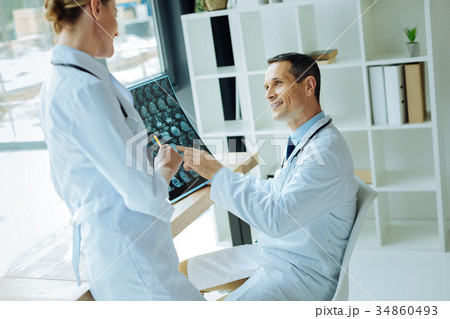 Joyful professional neurologists discussing an 34860493