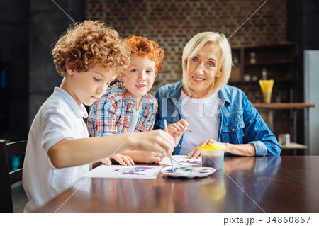 Kind elderly lady painting with grandsons at table 34860867