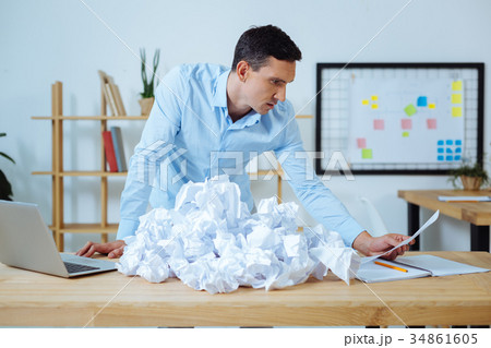 Attentive brunette man reading notes on document 34861605