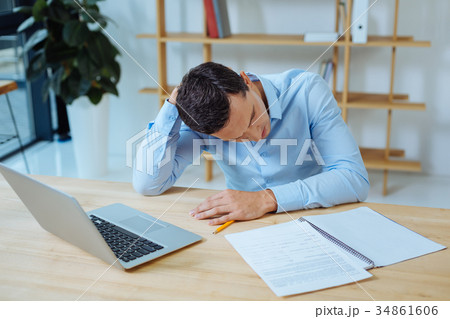 Disappointed man bowing head while working Disappointed man bowing head while working 34861606