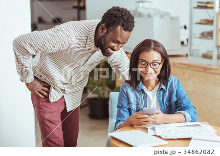 Cheerful man looking at his colleagues phone Cheerful man looking at his colleagues phone 34862082