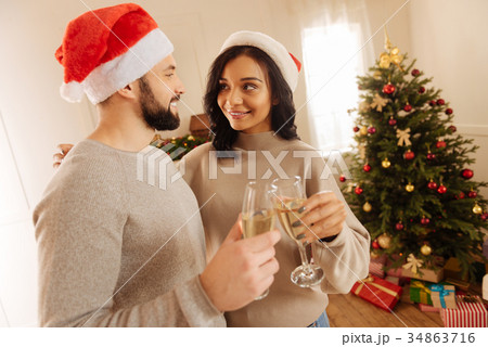 Charming couple clinking glasses and hugging Charming couple clinking glasses and hugging 34863716
