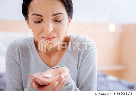 Smiling woman looking at the vitamins in her hand Smiling woman looking at the vitamins in her hand 34865173