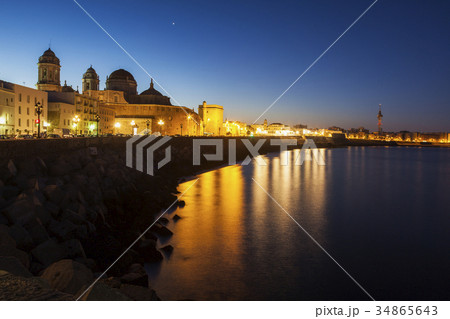 Spain, Andalusia, Cadiz, Cathedral de Cadiz and waterfront buildings at night 34865643