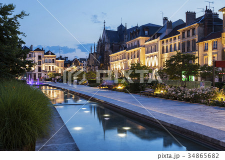 France, Grand Est, Troyes, Promenade along canal with illuminated buildings in background 34865682