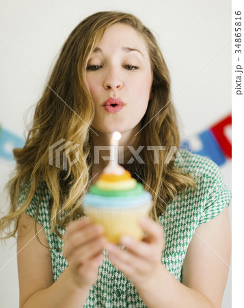 Mid adult woman blowing birthday candle 34865816