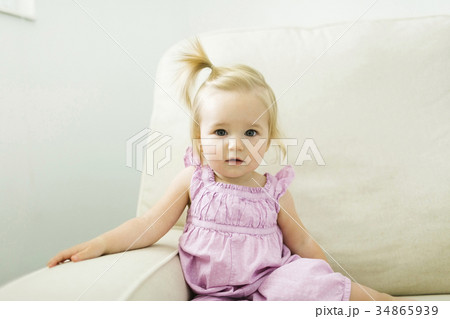 Portrait of baby girl (12-17 months) sitting on sofa 34865939