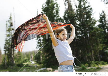 Girl (8-9) holding us flag in forest 34866260