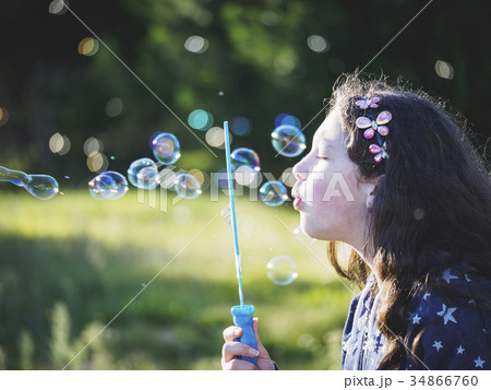 Girl (10-11) blowing bubbles 34866760