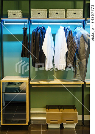 wooden wardrobe with clothes hanging on rail  34867773