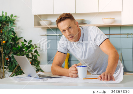 Serious unhappy man holding cup of tea 34867856