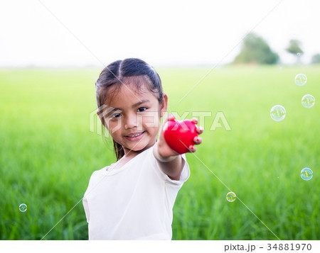 Happy little girl holding red heart and smiling. Happy little girl holding red heart and smiling. 34881970