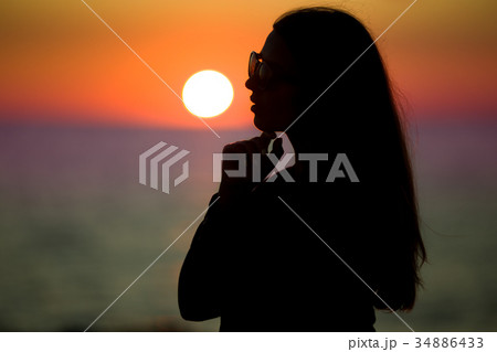 Silhouette of pretty woman over sunset on the 34886433