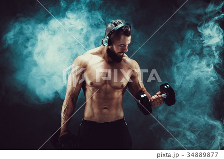 Man training muscles with dumbbells in studio on 34889877