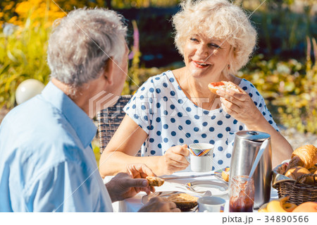 Happy elderly couple eating breakfast in their Happy elderly couple eating breakfast in their 34890566