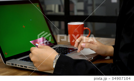 Business woman keying credit card information with mock up displ Business woman keying credit card information with mock up displ 34907104