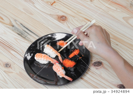hand holding sushi chopsticks on plate wooden hand holding sushi chopsticks on plate wooden 34924894
