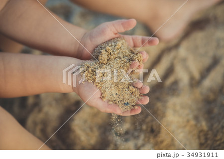 Child little hands holding sand close soft focus  34931911