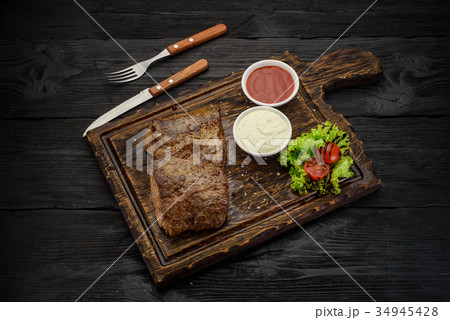 Grilled beef steak with sauces on a board. Grilled beef steak with sauces on a board. 34945428