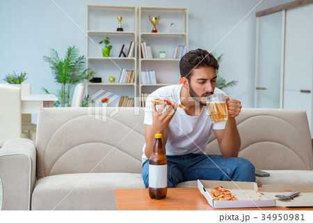 Man eating pizza having a takeaway at home 34950981
