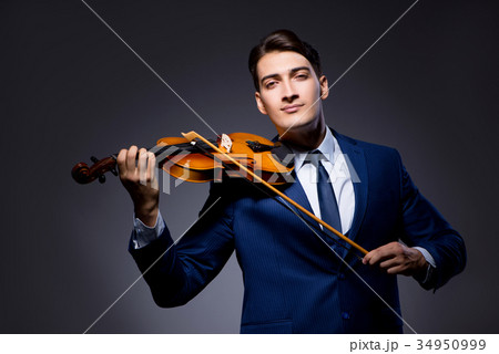 Young man playing violin in dark room 34950999