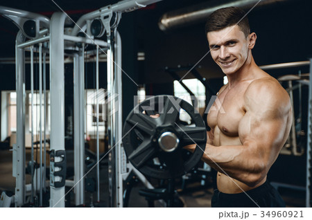 Handsome model young man training arms in gym Handsome model young man training arms in gym 34960921